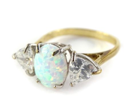 A 9ct gold three stone ring, set with imitation opal in four claw setting, and flanked by two triangular cut white paste ston