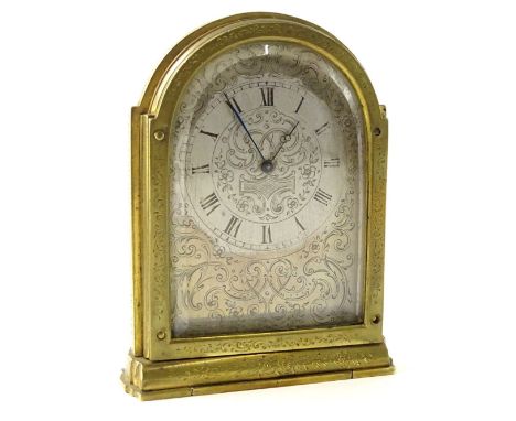 A 19thC engraved brass travelling clock in the manner of Thomas Cole, the arched silvered dial decorated with scrolls etc., o