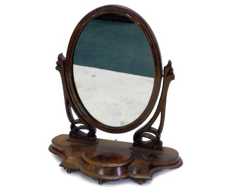 A Victorian mahogany dressing table mirror, the oval plate on pierced and carved supports, the shaped base with a hinged trin