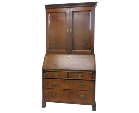 A George III oak bureau cabinet, the top with a moulded cornice above two panel doors, enclosing shelves and six small drawer