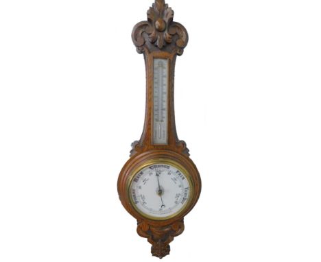 An early 20thC carved oak aneroid barometer, with silvered thermometer and porcelain dial, 88cm H.