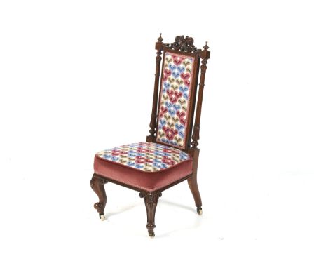 A mahogany upholstered chair.Carved decoration and finials to the top,with reeded columns,cabriole legs and ceramic casters.o