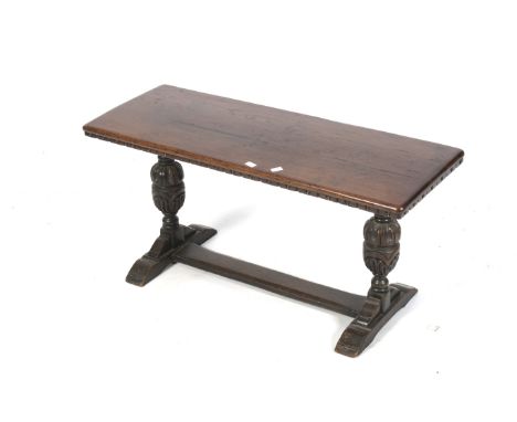 An early 20th century dark oak refectory style coffee table / bench. With carved frieze above turned cup and cover bulbous su
