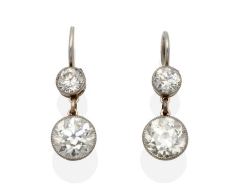 A Pair of Old Cut Diamond Drop Earrings, an old cut diamond in a white milgrain setting suspends a larger old cut diamond, to