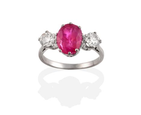 A Burmese Ruby and Diamond Three Stone Ring, an oval cut ruby spaced by two round brilliant cut diamonds in claw settings, to