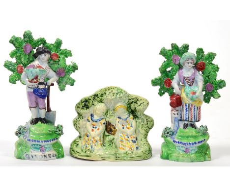 A Pair of Salt Pearlware Figures of Gardeners, circa 1810, he with a basket of flowers and a spade, she with a watering can, 
