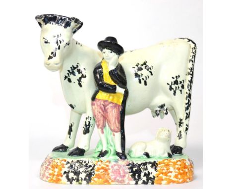 A Yorkshire Prattware Cow Group, circa 1800, modelled as a cowherd standing beside a cow, a calf at their feet, on a sponged 