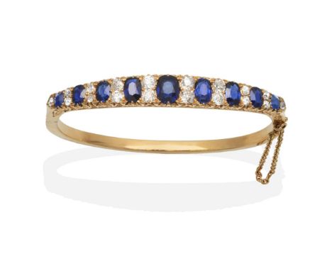 A Victorian Sapphire and Diamond Bangle, nine graduated oval cut sapphires, spaced by pairs of graduated old cut diamonds, in