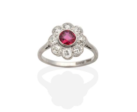 A Ruby and Diamond Cluster Ring, a round cut ruby within a border of milgrain set old cut diamonds, to knife edge shoulders, 