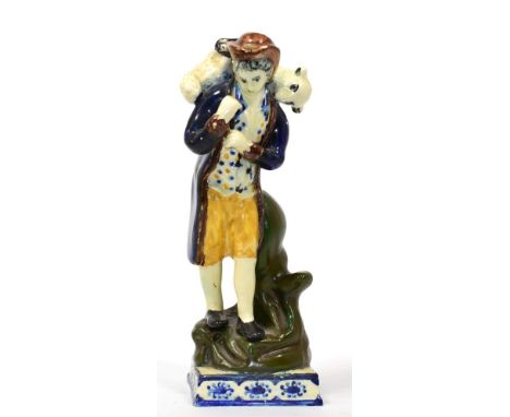 A Prattware Figure of the Lost Sheep, circa 1800, modelled as a standing shepherd holding a ewe across his shoulders standing