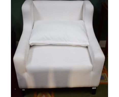 A COMFORTABLE EASY WING ARM CHAIR, covered in white fabric with loose cushion seat.