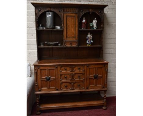 A SEVENTEENTH CENTURY STYLE OAK DRESSER, the breakfront top with a central bead moulded panel door and a small drawer, flanke