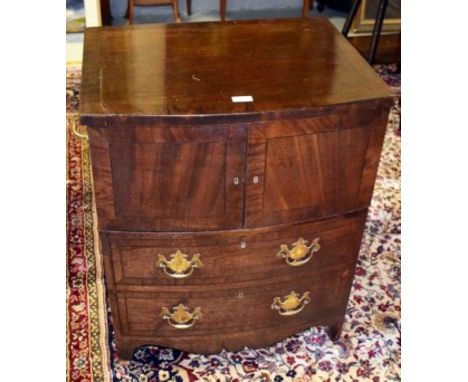 AN EBONY STRUNG AND BOW-FRONTED MAHOGANY COMMODE, with lift top and two brass carrying handles, two cupboard doors and two mo