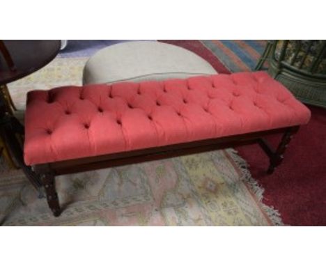 A MODERN OBLONG STOOL, with button seat, covered in red fabric, raised on turned supports, united by a shaped stretcher, 54" 