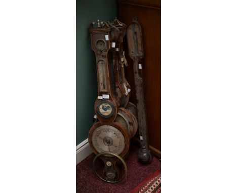 FOUR OLD WHEEL BAROMETERS, together with a stick barometer, all distressed. (5)