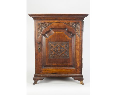 ANTIQUE CARVED OAK AND CROSSBANDED SMALL MURAL CUPBOARD, with dentil moulded cornice, panelled cupboard door and ogee bracket