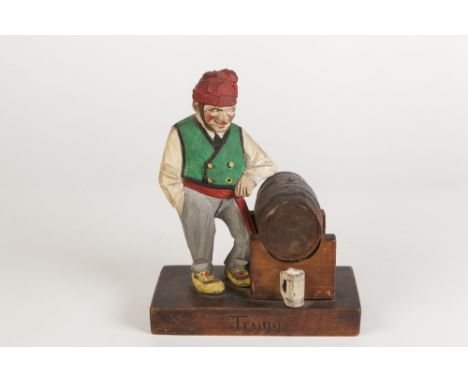 TRYGG-NORWEGIAN TWENTIETH CENTURY CARVED SOFTWOOD AND PAINTED FIGURE OF A MAN STANDING BESIDE A BEER KEG, carved signature to