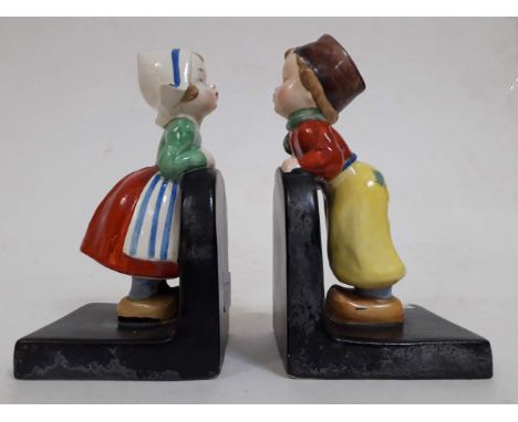 A set of early Goebel ceramic bookends with Dutch boy and girl looking over walls  
