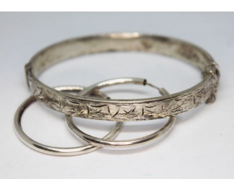 A silver bangle and a pair of silver earrings.  