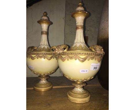 A pair of Royal Worcester blush ivory lidded vases.Condition:- Cracks, damage and repair to both tops, Cracks, damage and rep