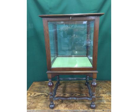 A 20TH CENTURY MAHOGANY GLASS TOP DISPLAY CABINET, THE GLAZED DOOR ENCLOSING A GLASS SHELF, ON TURNED LEGS JOINED BY WAVY STR