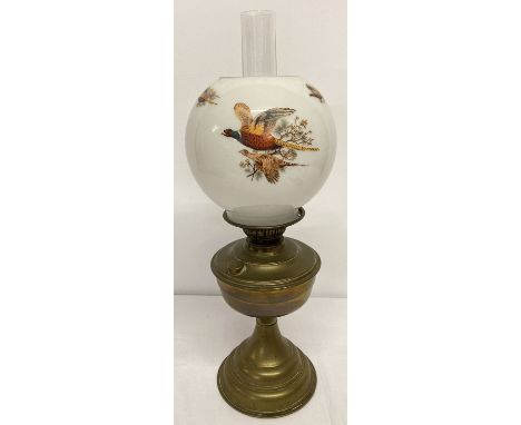 A vintage brass oil lamp with round glass opaque shade decorated with pheasants in flight. Complete with chimney. Small chip 