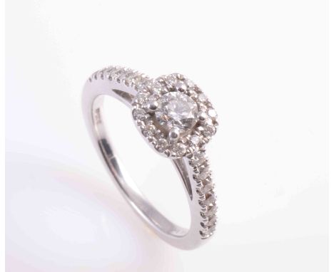 A DIAMOND RING, the brilliant cut diamond four claw set within a surround of twelve brilliant cut claw set diamond highlights