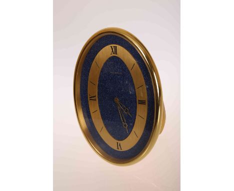 A JAEGER LECOULTRE STRUT CLOCK, oval, conforming gilt chapter ring with Roman numerals at III, VI, IX and XII, against a lapi