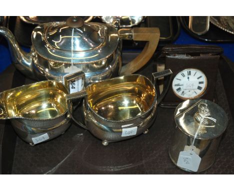 A lot comprising a three piece silver plated tea service, a tea caddy and a travel clock Condition Report: Available upon req