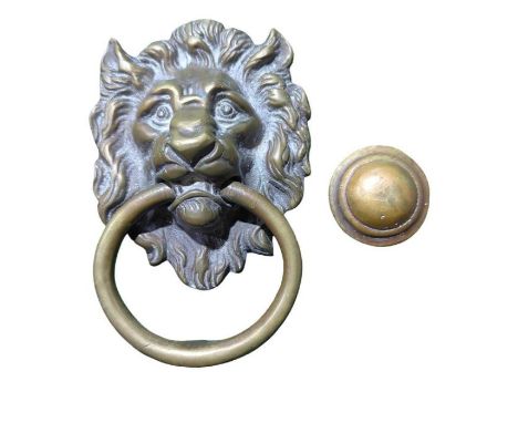 A cast brass lions head door knocker with loose ring and striker button