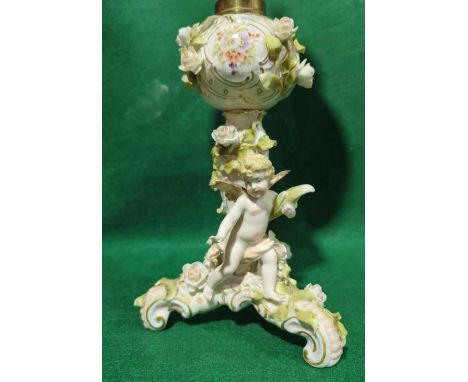 An early 20th Century encrusted porcelain oil lamp with cherub and flower decoration and with original chimney and yellow spi