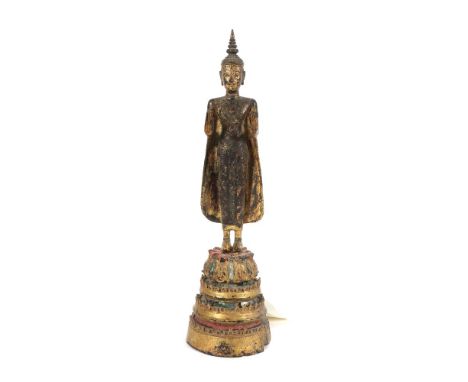 Stehender BuddhaThailand, 18./19. Jh., Holz vergoldet, part. rot eingefärbt, Sockel mit Glasbesatz, die Hände in Abhaya Mudra