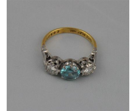 An 18ct. gold and platinum set light blue topaz and diamond dress ring, having central round brilliant cut topaz flanked by s