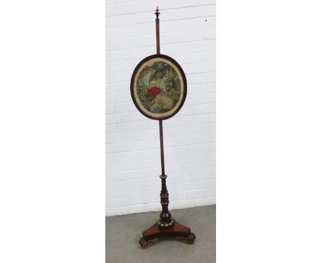 Early 19th century rosewood pole screen with brass finial and mounts and a triform platform base with scrolling feet, 144cm h
