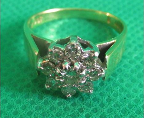 A diamond cluster ring, the brilliant cut diamonds claw mounted above raised engraved 18ct shoulders.