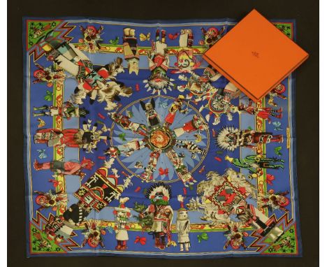 An Hermès silk scarf,'Kachinas', designed by Kermit Oliver, blue ground with a native Indian design, with ribbon, in box and 