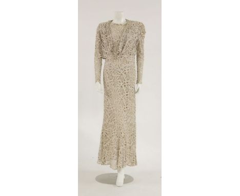 A beige lace dress,c.1930, with cream stitched floral pattern over a satin layer, with matching bolero shawl, two-button fast