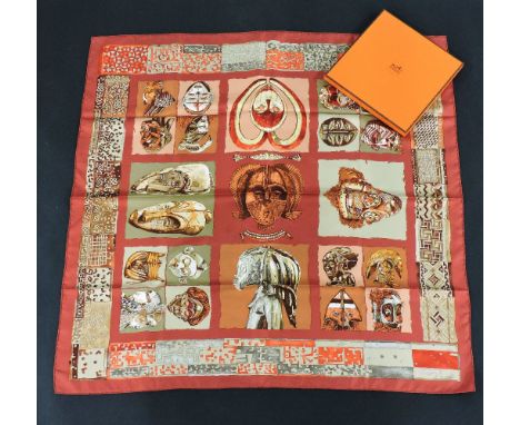 An Hermès silk scarf,'Persona', designed by Loic Dubigeon, red ground with printed African design, with ribbon, box and outer