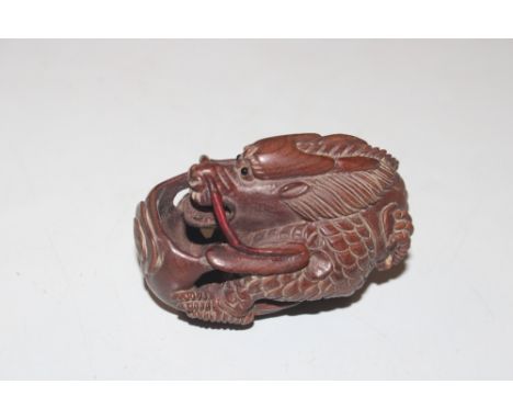 A carved wooden Netsuke in the form of a dragon