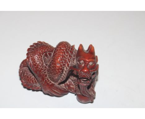 A carved wooden Netsuke in the form of a dragon 
