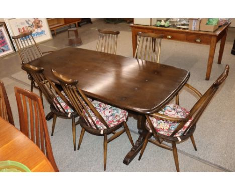 An Ercol refectory type dining table and a set of six stick back chairs, four standards two elbows 