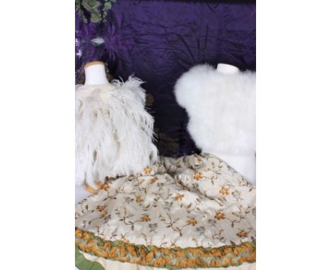 A late 19th Century floral silk skirt; a panel of 19th Century mauve silk (with damage), a white ostrich feather cape, a whit