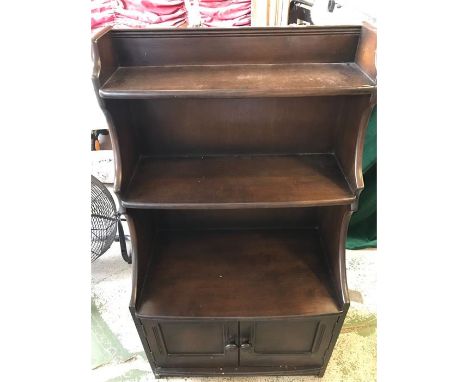 An Ercol waterfall bookcase with cupboard under.