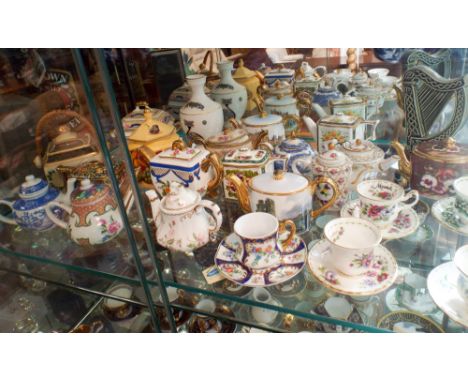 Three shelves of miniature collectable cabinet cups and saucers to include Coalport, Royal Albert, miniature teapots etc 