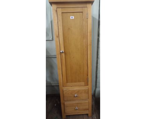 A tall narrow good quality light oak cupboard with 2 drawers under