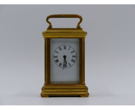 A  MINIATURE BRASS CASED CARRIAGE CLOCK WITH WHITE ENAMEL DIAL.   H.9cms (INCLUDING HANDLE)