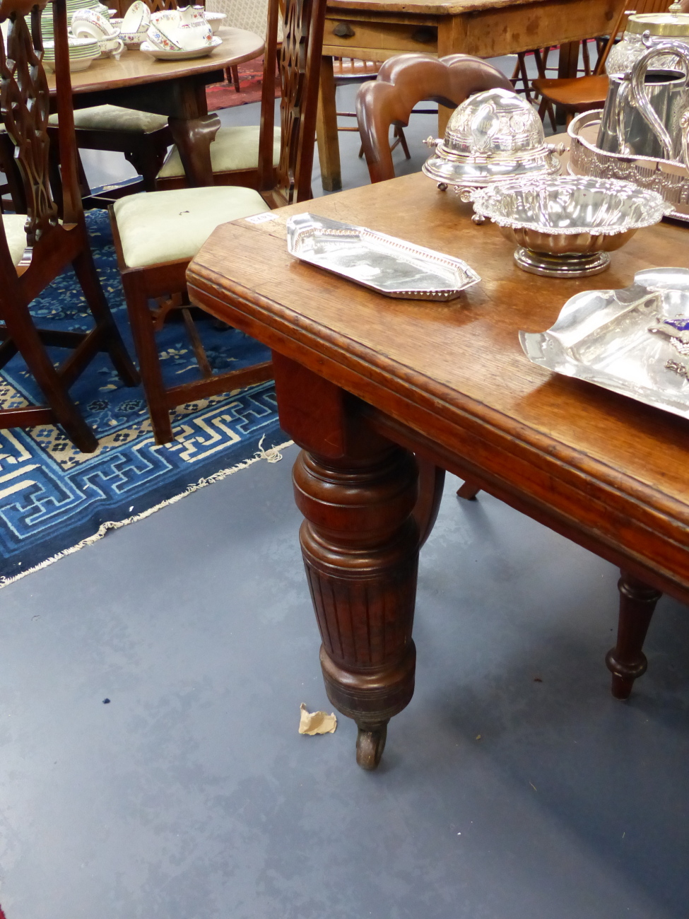 A LARGE VICTORIAN OAK EXTENDING DINING TABLE STANDING ON ...