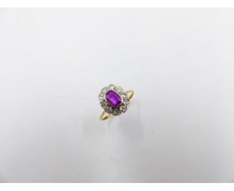 AN 18ct YELLOW GOLD AND PLATINUM STAMPED RUBY AND DIAMOND CLUSTER RING. THE CENTRAL OVAL RUBY SURROUNDED BY TEN BRILLIANT CUT