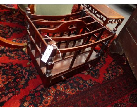 A LATE REGENCY MAHOGANY FOUR DIVISION CANTERBURY WITH APRON DRAWER, RING TURNED TAPERED LEGS ENDING IN BRASS CASTORS.