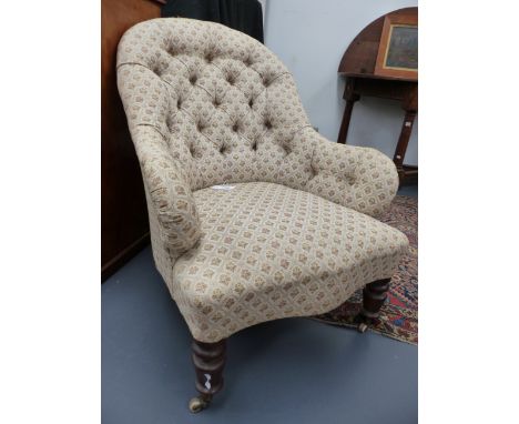 A VICTORIAN UPHOLSTERED BUTTON BACK ARMCHAIR ON RING TURNED FRONT LEGS ENDING IN CERAMIC CASTORS.